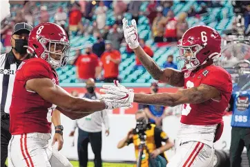  ?? CHRIS O’MEARA/ASSOCIATED PRESS ?? Alabama wide receiver DeVonta Smith, right, gets congratula­tions from teammate John Metchie III after the Heisman Trophy winner made one of his three TD catches during the Crimson Tide’s 52-24 rout of Ohio State.