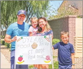  ?? (AP/Cheyanne Mumphrey) ?? Nick, Evelyn, Erin and Dylan Pfeifer stand together near their home in Chandler, Ariz., holding a hand-drawn sign promoting a food drive. “It’s been hard to interact with people, especially now, so this provides a safe way to do that. I just wanted to provide him a way to make an impact,” Erin Pfeifer said.