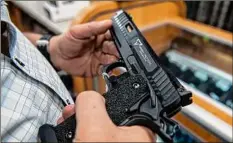  ?? Brittainy Newman / Associated Press ?? A customer checks out a handgun for sale in 2022 in Hempstead, New York. The Supreme Court’s so-called Bruen decision changed the test that lower courts had long used for evaluating challenges to firearm restrictio­ns. Judges should no longer consider whether the law serves public interests like enhancing public safety, judges said.