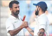  ??  ?? Indian captain Virat Kohli greets teammate Cheteshwar Pujara (L) at the end of the second day's play of the second Test.