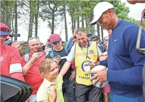  ?? THOMAS J. RUSSO/USA TODAY SPORTS ?? Tiger Woods signs autographs Wednesday after a practice round for the British Open at Carnoustie Golf Links.