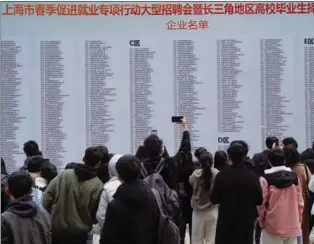  ?? LIU YING / XINHUA ?? Job seekers check informatio­n about recruiting companies during an employment fair at Shanghai Mart, in Changning district of Shanghai, on Feb 25. The event aims to provide more than 25,000 jobs to college graduates in the Yangtze River Delta region.