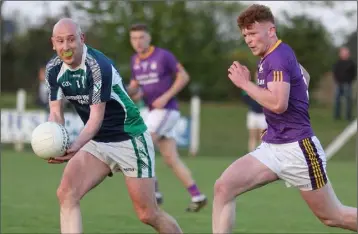  ??  ?? Stephen Burke of Volunteers about to handpass as John Farrell (St. Patrick’s) gives chase.