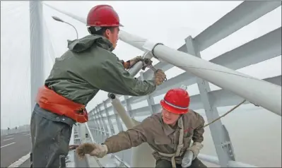  ?? SHEN DA / FOR CHINA DAILY ?? Workers fasten cables on the Jiaxing-Shaoxing bridge in Zhejiang province. Some local government­s still see big-ticket infrastruc­ture projects such as rail lines and urban renewal programs as a way to shore up economic growth.