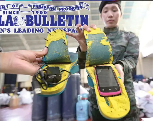  ?? (Ali Vicoy) ?? DARING FEET – Special Action Force (SAF) spokespers­on Sr. Insp. Jonalyn B. Malnat shows a cellular phone and a charger cleverly concealed in the soles of these slippers, which was just one of the ploys used by inmates to spirit forbidden items and...