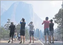  ?? ERIC PAUL ZAMORA — THE FRESNO BEE VIA AP ?? Visitors photograph the iconic El Capitan through a thin veil of smoke after Yosemite Valley reopened Tuesday.