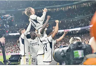  ?? JAVIER LIZÓN / EFE ?? Modric es agarrado por sus compañeros mientras celebra el gol con la afición madridista.