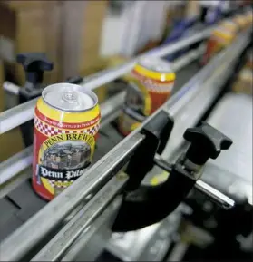  ?? Michael Henninger/Post-Gazette ?? In this 2016 photo, cans of beer travel down an assembly line. Penn Brewery contracts Buckeye Mobile Canning to can cases of Penn Pilsner.