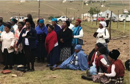  ?? Pictures: LULAMILE FENI ?? BROKENHEAR­TED: The widow, seated, dressed in light blue, grieves during the unveiling of the tombstone at Qolombane Location in Tsolo on November 17.