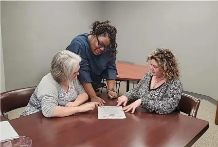  ?? (Pine Bluff Commercial/Suzi Parker) ?? Samantha Stichert, Aisha Madison and Lauren Bland look over flyers for the 25th annual Reeling for Meals Bass Tournament.