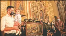  ?? (AP/Vadim Ghirda) ?? A man of the Armenian community in Romania holds a young child during the Easter religious service.