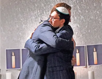  ?? DEB CRAM/SEACOASTON­LINE ?? Portsmouth Mayor Deaglan McEachern hugs Rabbi Berel Slavaticki after lighting a candle during an evening of solidarity, unity and prayer at the Seacoast Jewish Community Center on Tuesday.