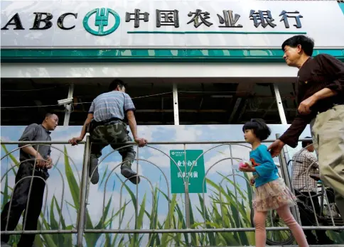  ??  ?? People walk past a branch of Agricultur­al Bank of China in Shanghai, China. – Reuters photo