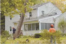  ??  ?? RECOVERY WORK: Nick Mitton and Rob Retelle of Retelle Tree Corp. maneuver a toppled tree off a house on Old Village Drive in North Andover.