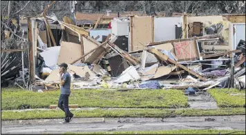  ?? GERALD HERBERT / ASSOCIATED PRESS ?? A man on Wednesday walks past a destroyed home in the aftermath of Tuesday’s tornado that tore through the New Orleans East section of New Orleans. More than 900 properties were destroyed or seriously damaged.