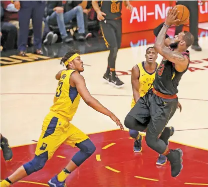  ??  ?? LeBron James (d) tira frente a la presión de Myles Turner, de Indiana