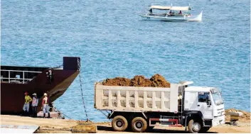  ?? — Reuters ?? A truck loads rocks and soil containing nickel-ore minerals into a barge in the mining town of Sta Cruz Zambales. Philippine­s economic growth eased to 6.4 per cent in the first quarter of 2017, due to a slowdown in public spending.