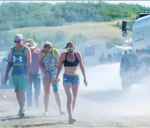  ?? MICHAEL BELL ?? Victoria Faith, centre, and her friends keep cool in the steamy temperatur­es with spray from a water truck at Country Thunder in Craven.