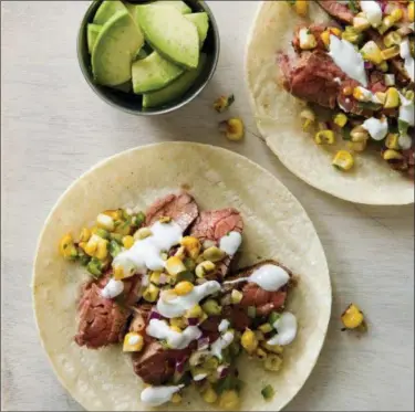  ?? JOE KELLER/AMERICA’S TEST KITCHEN VIA ASSOCIATED PRESS ?? This photo provided by America’s Test Kitchen shows flank steak tacos with charred corn salsa in Brookline, Mass.