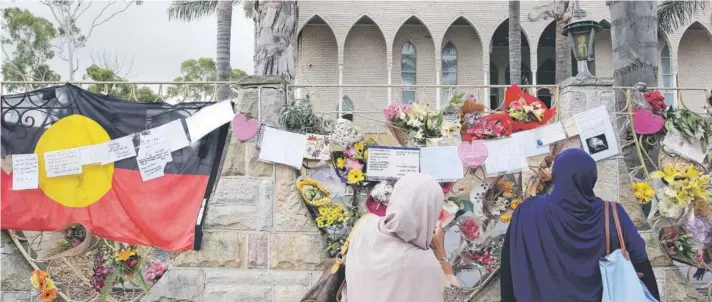  ??  ?? Mujeres musulmanas leen mensajes colgados en el muro de la Mezquita Lakemba, en Australia, en homenaje a las 50 víctimas de los ataques de Nueva Zelandia del 15 de marzo.