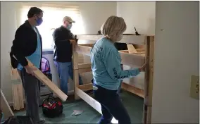  ?? SHEENA HOLLAND DOLAN — THE NEWS-HERALD ?? Sue Lach (front) and other volunteers for the Lake and Geauga County chapter of Sleep in Heavenly Peace construct a bunk bed in one of the Painesvill­e homes they were delivering to on March 20.