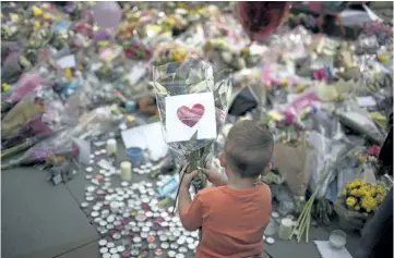  ?? EMILIO MORENATTI/THE ASSOCIATED PRESS ?? A child places flowers in a square in central Manchester, Britain, on Wednesday.