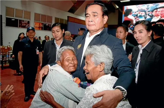  ?? AP ?? Elderly voters hug Thai Prime Minister Prayuth Chan-ocha as he attends a government-sponsored election event in Nakhon Ratchasima, Thailand. Prayuth, who toppled Thailand’s last elected government in a 2014 coup, has been trying to moderate his image in a bid to hold on to his position by winning over the Thai electorate.
