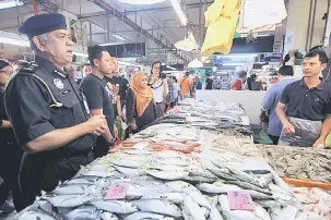  ?? — Gambar Bernama ?? TINJAU: Aris (kiri) meninjau harga ikan ketika menjalanka­n pemeriksaa­n di Pasar Awam Larkin, Johor Bahru semalam.