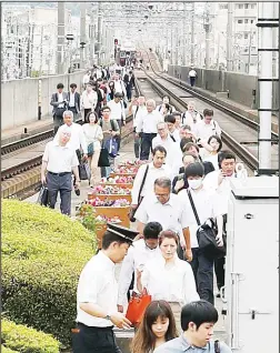  ?? (AP) ?? Passengers walk on railroad as train service was suspended following an earthquake in Ikeda, Osaka on June 18. A strong earthquake shook the city of Osaka in western Japan on Monday morning, causing scattered damage including broken glass and partialbui­lding collapses.