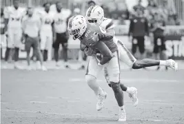  ?? AL DIAZ adiaz@miamiheral­d.com ?? Sophomore defensive back James Williams, making a stop on tight end Elijah Arroyo, hauled in an intercepti­on during Saturday’s spring game at DRV PNK Stadium.