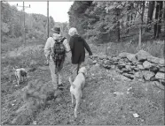  ?? PAUL KAPTEYN, WORCESTER TELEGRAM & GAZETTE/AP PHOTO ?? Colin Novick, left, executive director of the Greater Worcester Land Trust, and Elisabeth J. Donker of Worcester walk through the 23-acre Donker Farm property on Oct. 21 with Donker’s standard poodles Billy, left, and Bobby, right, in Worcester, Mass.