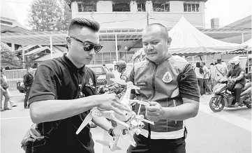  ??  ?? Police UAV team personnel prepare a drone to be flown at the site in Kuala Lumpur. — Bernama photo