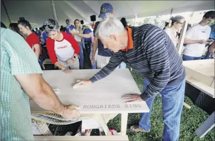  ?? Stephanie Zollshan / The Berkshire Eagle via Associated Press ?? Hundreds of volunteers gather at The Common in Pittsfield, Mass., for a community day of action on Saturday, Aug. 10, 2019, to build wooden tables and benches with engravings inspired by the prompt: “The Berkshires Make …”. The day was part of Yo-yo Ma’s Bach Project, and in partnershi­p with Hancock Shaker Village, volunteers made 36 tables and a community mural, and planted a tree in memory of those lost to addiction, gun violence and war.