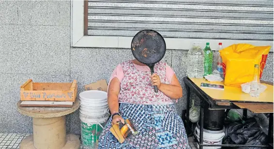 ?? MANUEL FERNÁNDEZ ?? En la calle. Una señora que vive, come y duerme en la calle tapa su rostro con una plancha bifera después de cocinar.