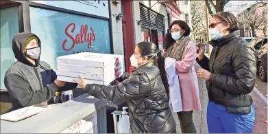  ?? Peter Hvizdak / Hearst Connecticu­t Media / New Haven Register ?? Ivan Parra, a Sally's Apizza employee serves free takeout pizza to Yale New Haven Hospital employees Alienne Salleroli, R.N., Priscilla Steve and Curri Bower, R.N.