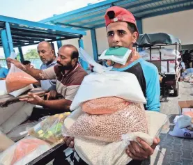  ?? SAID KHATIB/AFP/GETTY IMAGES ?? Palestinia­n men collect food at a United Nations compound in the Rafah refugee camp in the southern Gaza Strip on Sept. 1.