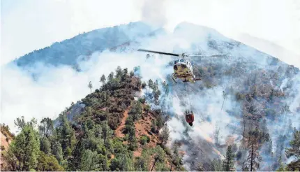  ?? ANDREW KUHN/AP ?? A helicopter gathers water from the Merced River to fight the Ferguson Fire along steep terrain behind the Redbud Lodge along Highway 140 in Mariposa County, Calif., on Saturday.