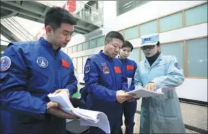 ??  ?? Chen Dong, Liu Wang and Liu Yang talk with a team member during flight training at the center.