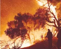  ?? AP FOTO ?? FANNED BY WINDS. Firefighte­rs knock down wind-fanned flames as they advance on homes atop Shepherd Mesa Road in Carpinteri­a.