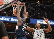  ?? ?? UConn’s Adama Sanogo (21) dunks past Georgetown forward Bradley Ezewiro during the first half on Saturday. Nick Wass/Associated Press