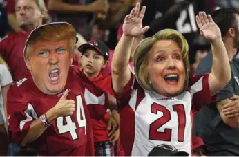  ?? NORM HALL/GETTY IMAGES FILE PHOTO ?? Arizona Cardinals fans wear masks of Donald Trump and Hillary Clinton during a game in October.