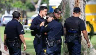  ?? Marco Garcia/Associated Press ?? Honolulu police officers gather near the scene of a shooting Sunday near Diamond Head State Monument in Honolulu.