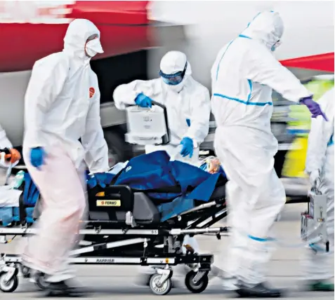  ??  ?? A patient from France who is seriously ill with the coronaviru­s is transferre­d from a plane after landing at Dresden Internatio­nal Airport in Germany
