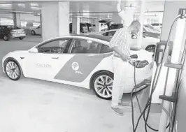  ?? THOMAS WINTER / COURTESY ?? A customer powers his electric vehicle at an FPL charging station in the Brightline station parking garage in West Palm Beach in 2019.