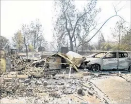  ??  ?? A CAR BURNED by the Detwiler fire rests outside a leveled structure near Mariposa, Calif. At least six other smaller blazes erupted across the state Monday.