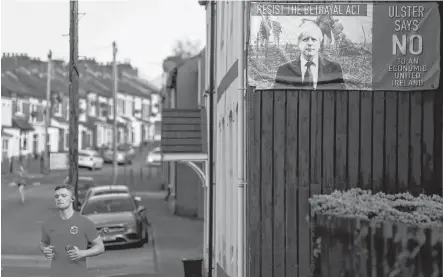  ?? REUTERS ?? A man jogs next to a poster depicting Britain’s Prime Minister Boris Johnson, as the COVID-19 restrictio­ns ease, in Belfast, Northern Ireland on April 12.