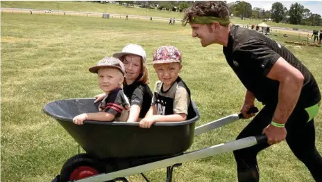  ?? Lacey Photos: Bev ?? TOUGH EVENT: Aaron Sutcliffe pushes (from left) Jayden, Willow and Austin Sutcliffe in a wheelbarro­w at the Kryptonite Challenge.