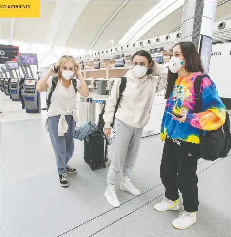  ?? PETER J THOMPSON / NATIONAL POST ?? Travellers adjust their protective masks at an internatio­nal check-in area at Toronto’s Pearson Internatio­nal Airport on Friday.