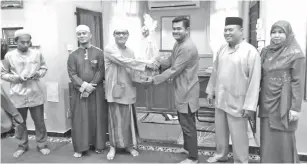  ??  ?? MOHD Fizal (tiga kanan) menyampaik­an sumbangan kuih raya kepada Rahimin dalam program berkenaan.