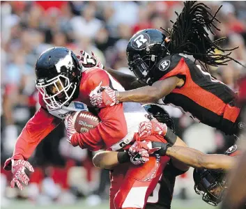  ?? JUSTIN TANG/THE CANADIAN PRESS ?? The Ottawa Redblacks’ Abdul Kanneh tries to strip the Calgary Stampeders’ Bakari Grant of the ball during the first half of Friday’s game in Ottawa.